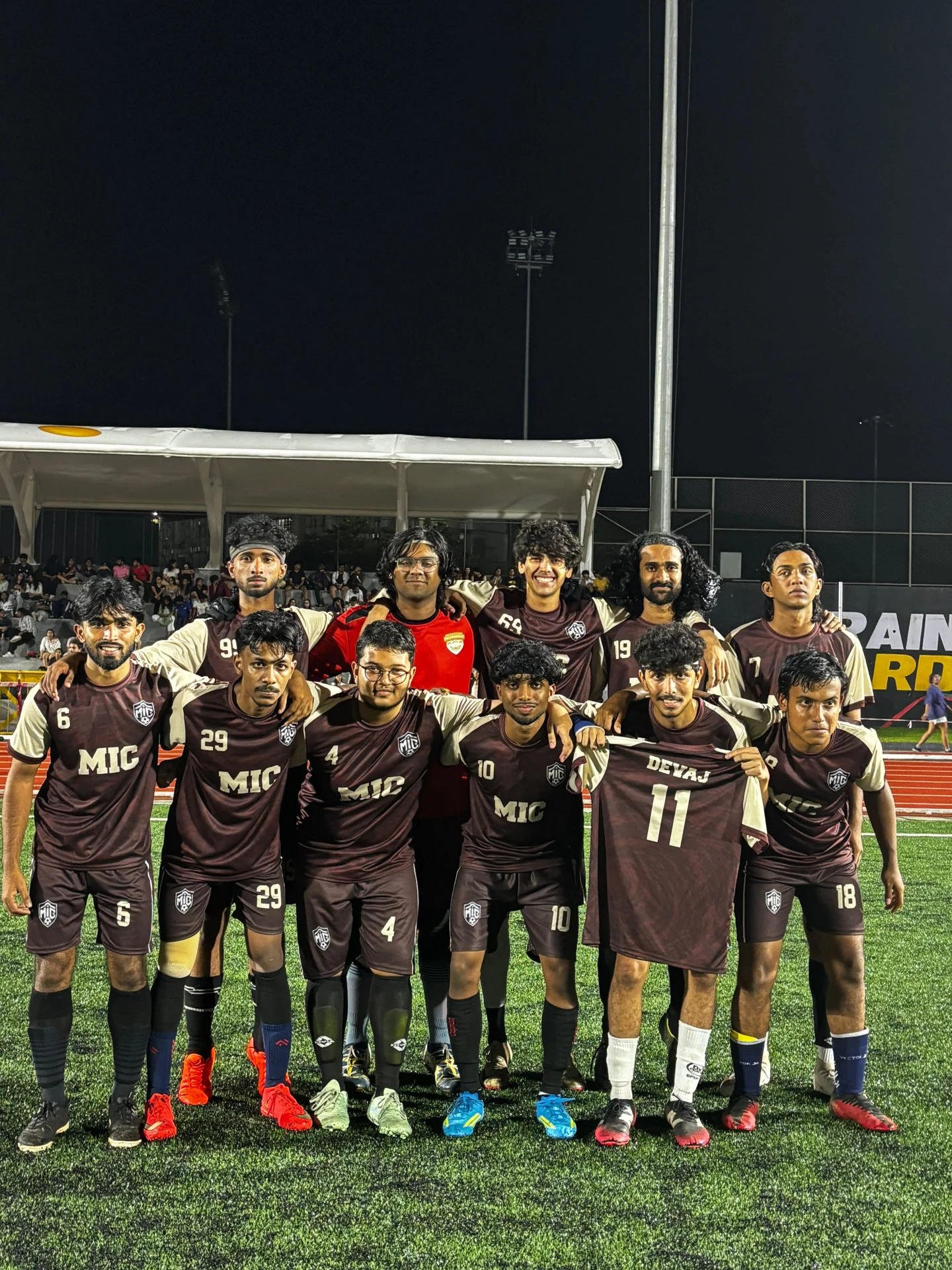 MIC Football Team wearing custom maroon and cream jerseys on the pitch at night