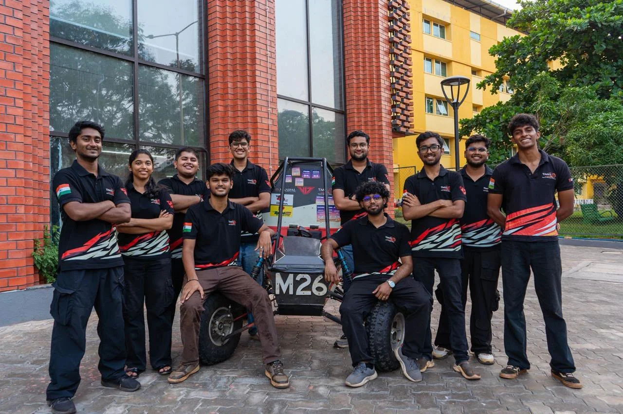 Student motorsport team wearing black and red custom polos beside their car